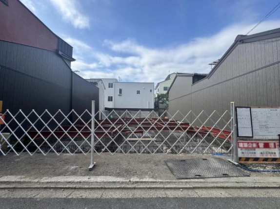 新築テナントの建設現場を正面から見た様子。伸縮式の仮囲い越しに基礎部分が見える