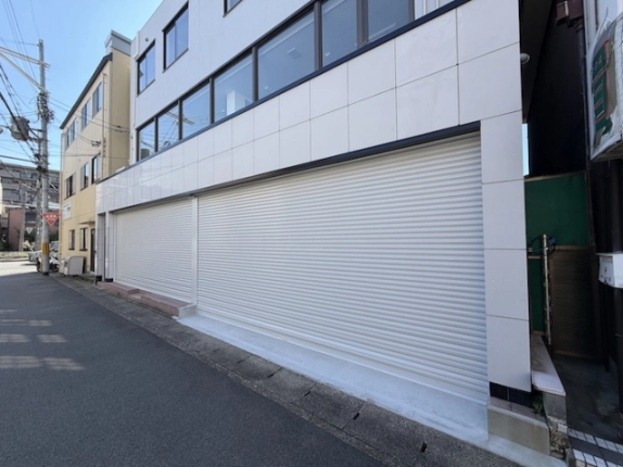 千代原口テナントビルを斜めから見た外観。1階駐車場の幅広いシャッターと2階の連続した窓