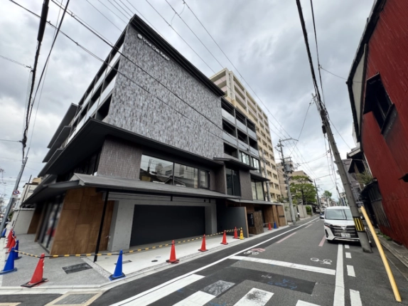 地下に貸店舗があるVine Oak Rabbiの外観。交差点から見た角の壁面と撮影時のカラーコーン