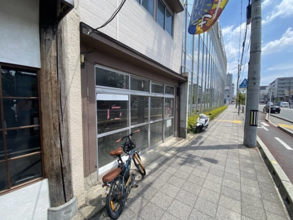 反対側から見た店舗のガラス戸と七条通の歩道。隣のガラス張りの建物も見える