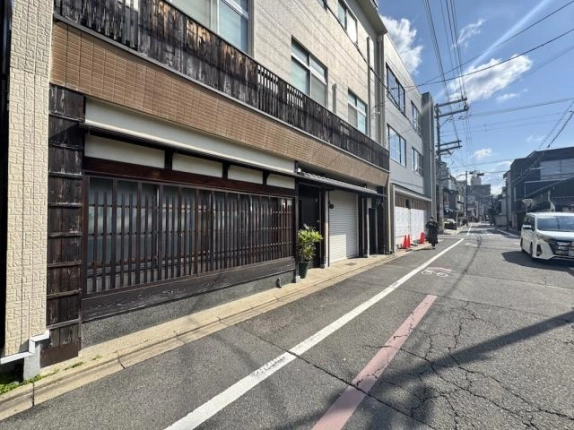 建物を左手に見た夷川通。格子窓のある外壁に沿って奥へ続く前面道路