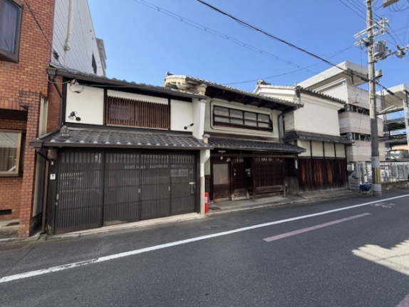 一棟貸店舗の正面を斜めから見た様子。木製格子と白い壁が並ぶ釜座通沿いの外観