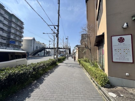 建物を右手に見た東大路通の歩道。両側の植え込みと奥に見える歩道橋
