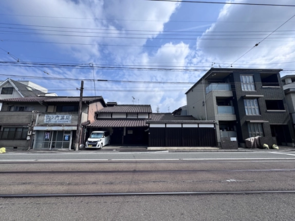 道路越しに見た山ノ内宮前町京町家の全景。両隣の建物と手前の線路