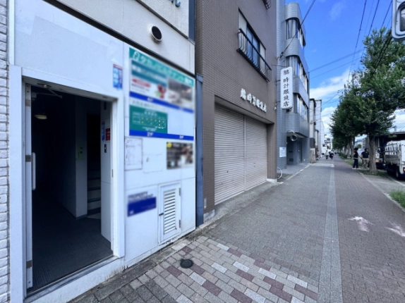 タカノビルの開いた共用入口と奥の階段。建物を左手に見た歩道