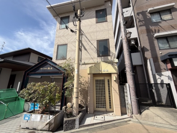 JR桃山駅前のコーポ鍋島を斜めから見た外観。建物下部の入口と左側の植栽