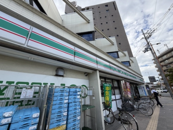 建物前の歩道から見上げた外観。1階のローソンの看板と2階の窓、店先の駐輪スペース