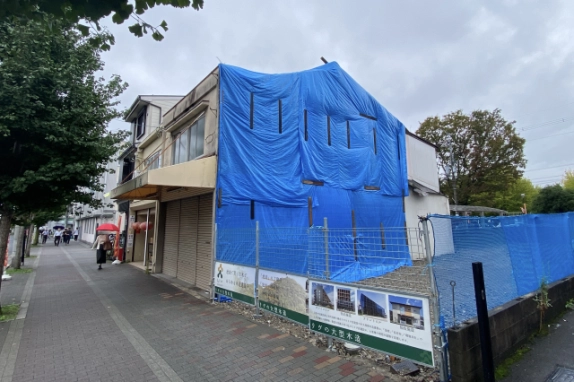 飛鳥井町店舗を右側から見た外観。青いシートで覆われた側面と歩道に面したシャッター