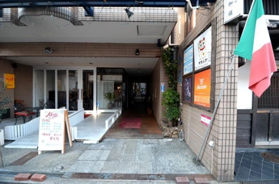 1階中央から奥へ続く通路の入口。赤いマットが敷かれ、右側のタイル壁にテナント看板が掲げられている