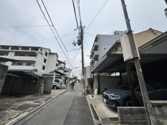 上京区分銅町の前面道路。電柱と電線が並ぶ住宅街の通りで、右手にカーポート、左手に白い中層マンション