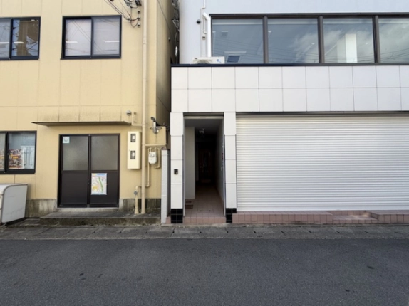 一棟貸事務所の入口。1階シャッターの左側にあるタイル敷きの出入口と上階の窓