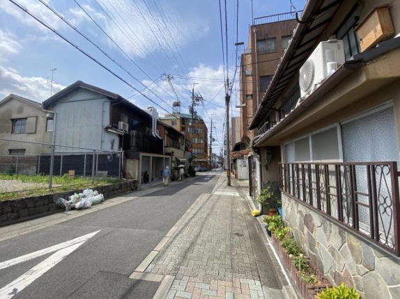北野天満宮に近い周辺の通り。右にブロック舗装の歩道と格子窓の住宅が並び、左には更地と家並みが奥まで続く