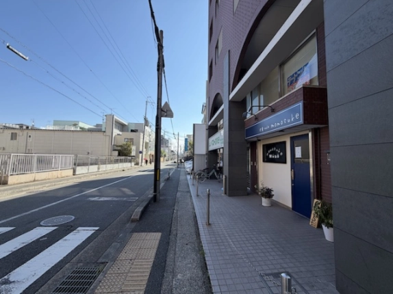 ツィンクルコート桂EASTの通り沿いの外観。右手に1階店舗の入口、左手に車道と歩道