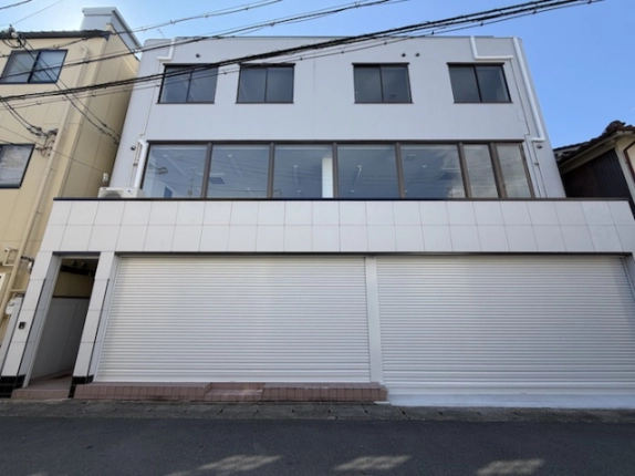京都市西京区山田六ノ坪町・千代原口テナントビルの正面外観。白い3階建ての壁面と大きなシャッター