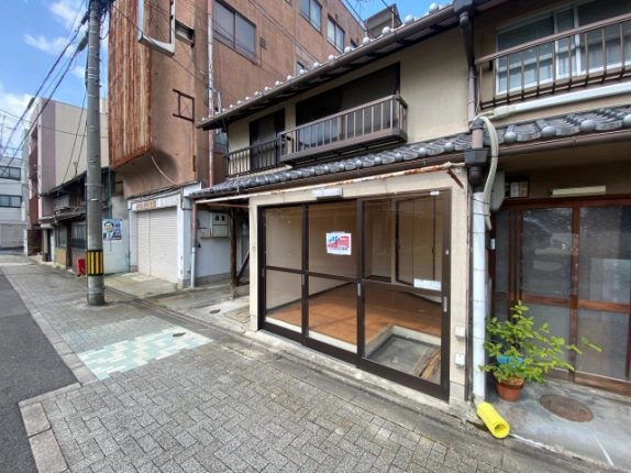 東堅町戸建店舗のガラス張りの正面。入口越しに見える床と店頭の舗装