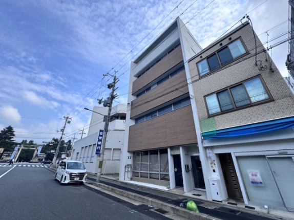 北野白梅町駅近くの西工務店ビルを見上げた外観。白い縁取りと茶色の壁面