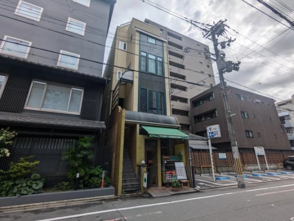 烏丸御池駅徒歩約2分の建物を斜めから見た外観。1階店舗の緑色のひさしと左側の外階段
