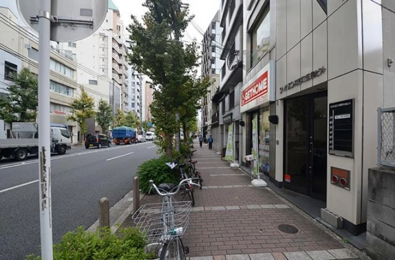 GEN SAKIZO河原町五条の共用入口と前面歩道。右手の黒い扉と建物案内、左手の街路樹