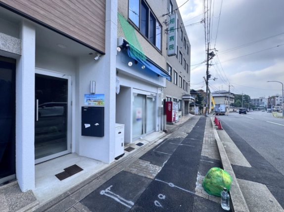 西工務店ビルを左手に見た前面道路。入口から奥へ続く歩道と隣接建物