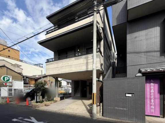 電柱越しに右斜め前から見た下京区のビル外観。右隣は濃いグレーのタイル張りの建物
