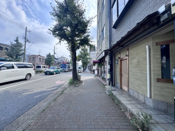 店舗を右手に見た今出川通。レンガ調舗装の歩道と車道沿いの街路樹