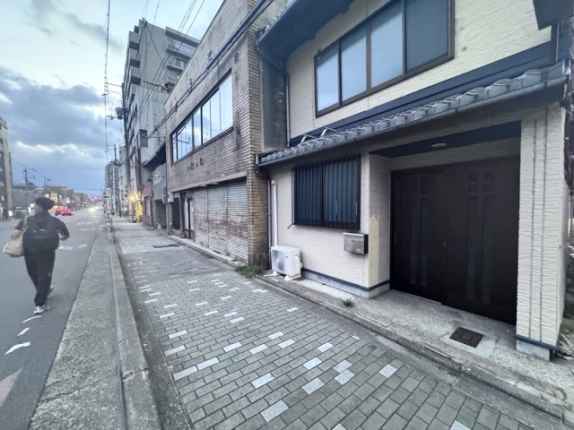 米屋町京町家の入口付近。格子窓と黒い玄関扉、建物前のタイル舗装の歩道