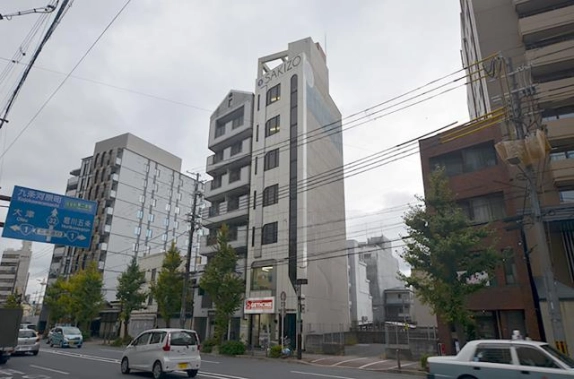 6階に貸事務所がある建物を斜めから見た外観。淡い色の側面と河原町通沿いの街路樹