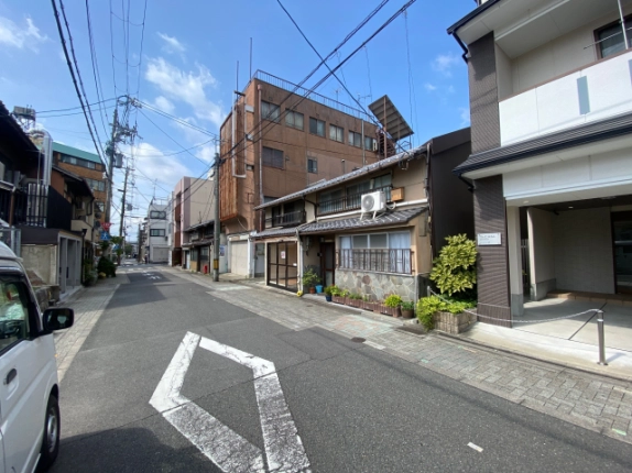 東堅町戸建店舗を右手に見た前面道路。瓦屋根の建物と周辺の街並み