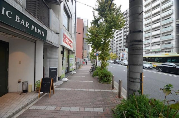 建物前の歩道を反対方向に見た様子。左手に1階店舗、右手に植栽と河原町通の車道