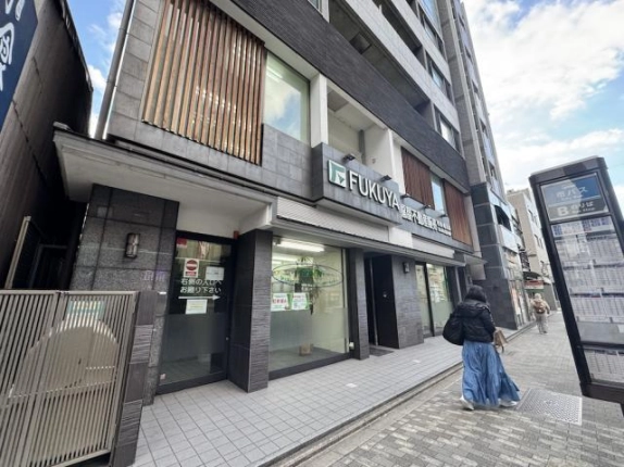 クオン四条柏屋町の低層部を反対側から見た様子。ガラス張りの1階と歩道沿いの案内板
