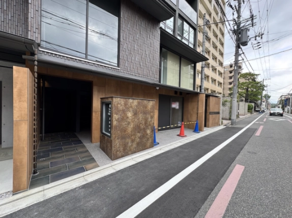 京都市中京区・Vine Oak Rabbiの建物入口まわり。茶色の壁面とタイル敷きの通路