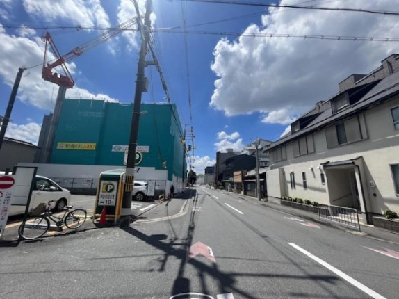 澤井ビル付近の前面道路。左手のコインパーキングと工事中の建物、右手の白い建物