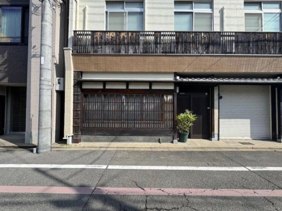 店舗正面の入口まわり。大きな木製格子窓と黒い扉、手前に置かれた鉢植え