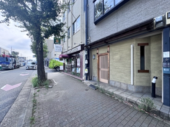 北野白梅町駅近くの貸店舗を斜めから見た外観。右手の格子戸と左手の歩道
