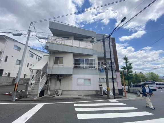 2階への屋外階段が見える建物側面。白い手すりの階段と横に並ぶ窓