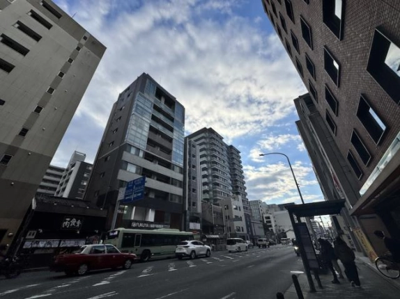 四条通の向かい側から見た建物と周辺の街並み。車道沿いに中高層のビルが並ぶ