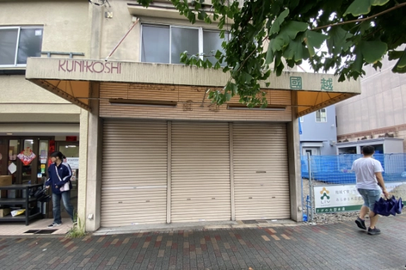 履物店跡の店舗正面。3枚のシャッターと店名が残る大きなひさし