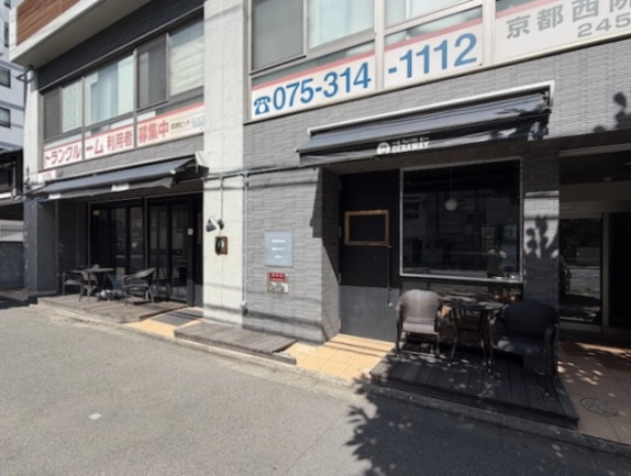 1階路面店舗を反対側から見た外観。グレーの外壁と通り沿いに並ぶ2つのひさし