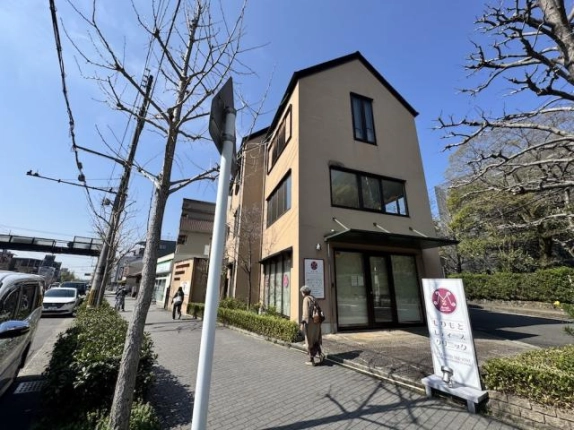 京都市左京区・東大路通沿いの伊佐ビル外観。角地に立つベージュ色の3階建てと街路樹