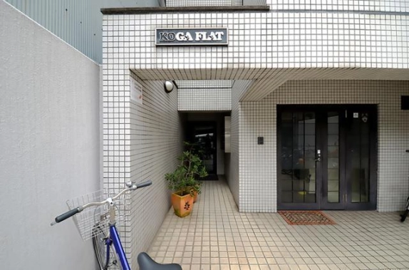 烏丸御池駅徒歩4分のKOGAフラット入口。館名表示と奥へ続く通路、右側のガラス扉