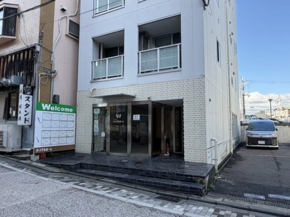 Casa La Vitaの1階店舗正面。ガラス張りの入口と庇、右側に見える駐車場