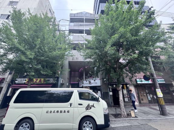 木屋町不動ビルを正面から見上げた外観。上階のバルコニーと建物前の並木