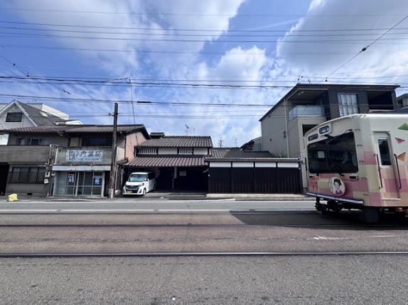 三条通の向かい側から見た京町家。手前を通る嵐電と瓦屋根の建物