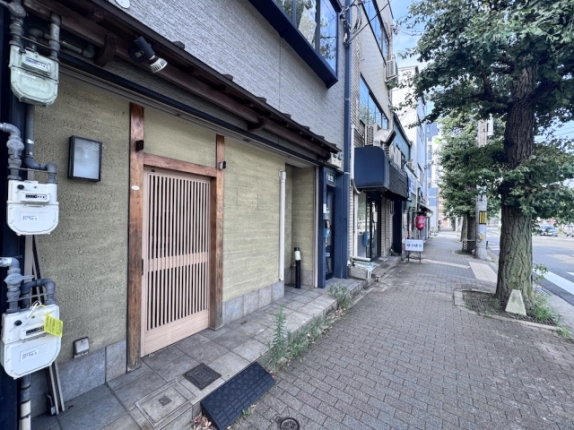 1階貸店舗の入口を近くから見た様子。木製格子戸と足元の段差