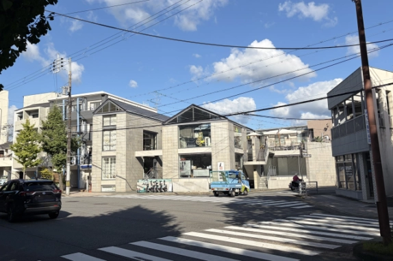 北山の交差点から横断歩道越しに見たツリーズビル。三角屋根の2棟が並び、大きなガラス窓とグレーのブロック壁が目立つ外観