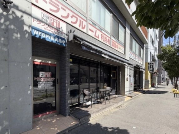 京都市右京区・グランドーリア西院の1階店舗外観。黒いひさしとガラス面、店舗前に置かれたテーブル