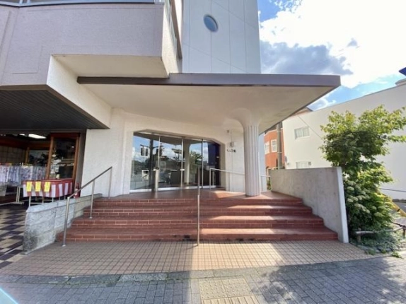 じょい下鴨の建物入口。大きなひさしの下のガラス扉と赤茶色の階段、中央の手すり