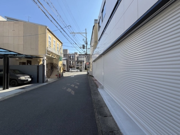 上桂駅周辺の前面道路。右手にビルのシャッター、左手に向かいの建物と車庫
