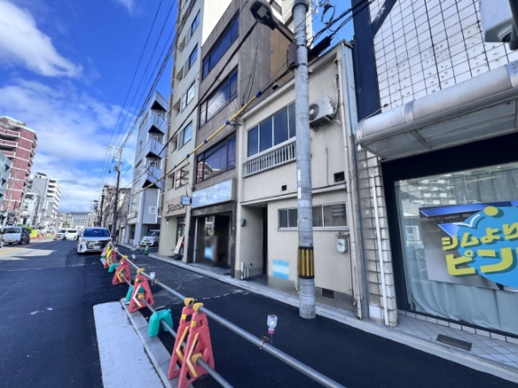 京都市中京区・壬生馬場町の一棟貸店舗を斜めから見た外観。淡い色の2階建て建物と周辺店舗