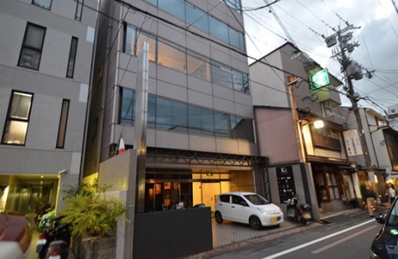 1C区画があるSOHOビルを斜めから見た外観。各階の窓と隣接する町家の街並み
